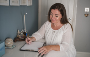 Photograph of Siobhan Carrig sitting at a desk writing on a note pad