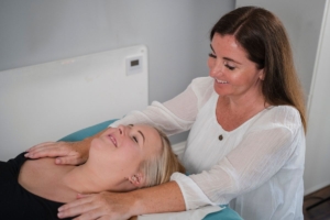Image of Siobhan Carrig with her hands on the shoulders of a lady lying down to help reduce her stress